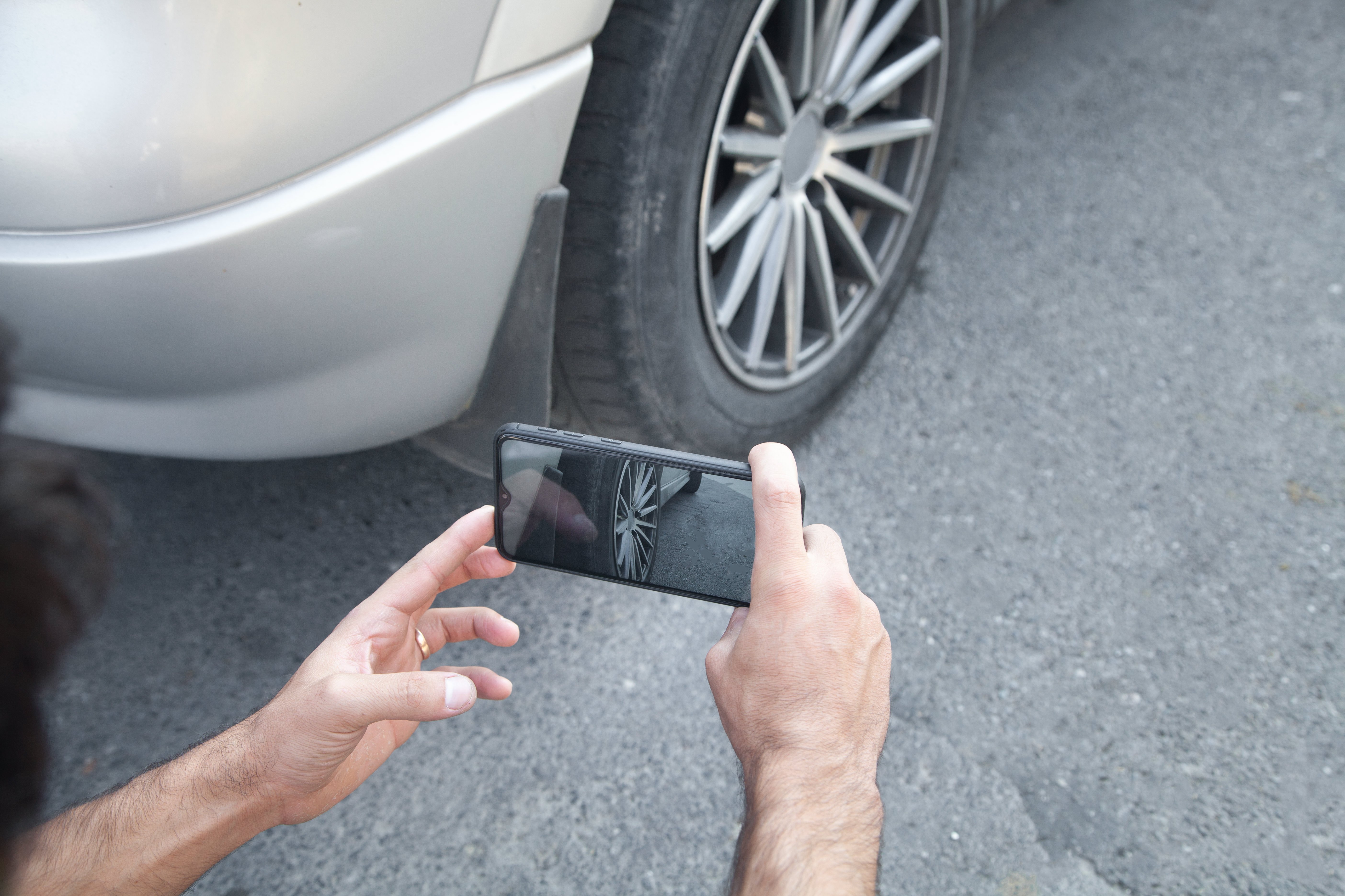 Person som tar ett foto av ett bilhjul på sin telefon